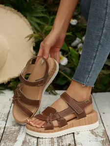 Close-up detail of brown platform wedge sandals with wood-grain texture and white sole