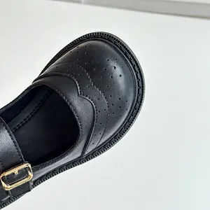 Gros plan de chaussures Mary Jane en cuir noir pour enfants avec détails brogues