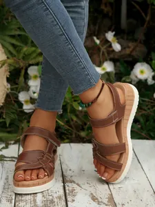 Close-up of stylish brown platform wedge sandals with decorative white stitching detail