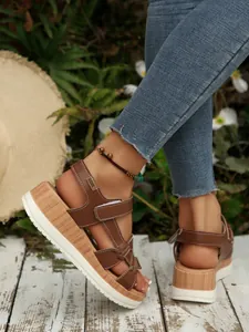 Detail shot of brown platform sandals with wood grain midsole and strappy design.