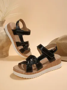 Detailed macro view of black platform sandals with stylish wood-grain wedge heel