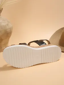 Detailed view of the anti-slip white ribbed sole on black wedge platform sandals for women