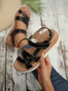 Macro view of black platform sandals featuring knotted straps and contrast white stitching.