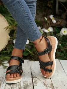 Close-up of black platform sandals with wedge heels and white contrast stitching