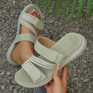 Sandales à plateforme vert sauge avec bandes velcro présentées sur du gravier.