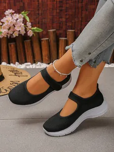 Close-up of black breathable mesh Mary Jane sneakers with white soft soles on feet