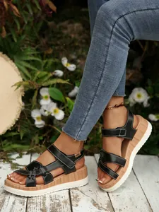 Womens black platform wedge sandals with white stitching in a stylish outdoor setting