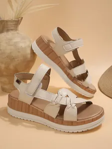 Macro detail view of women's cream platform wedge sandals featuring woven leather straps.