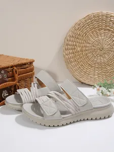 Détail de sandales de plage grises à plateforme avec velcro et cordons élastiques.