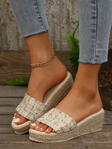 Primer plano de elegantes sandalias con cuña de tweed para mujer con fondo de madera rústica.