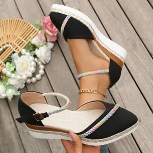Detailopname van zwarte sleehak sandalen met puntige neus en regenboog strasbandjes