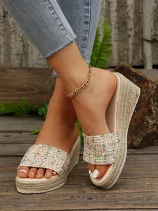 Vista detallada de elegantes sandalias con cuña de alpargata tejida de colores sobre madera