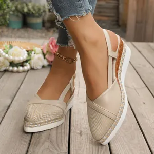 Detailopname van beige sleehaksandalen met puntige neus en gevlochten touwzool.
