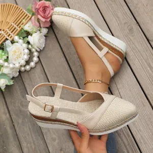 Gedetailleerd overzicht van beige espadrille sandalen met sleehak op houten vloer