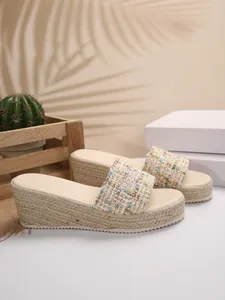 Vista detallada de sandalias de cuña para mujer con correas de tweed y suela de plataforma de yute.