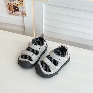 Dettaglio di sandali grigi da esterno per bambini con velcro e fodera a scacchi.