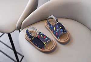 Navy blue children's sandals with colorful dinosaur prints and soft tan soles.