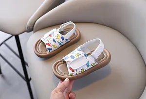 Detailed view of toddler sandals with colorful dinosaur print and soft brown soles