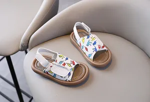 White children's outdoor sandals with colorful dinosaur prints and soft brown soles