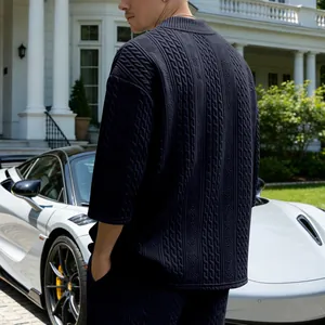 Rückansicht eines Mannes in einem dunkelblauen, strukturierten Oversize-T-Shirt mit Zopfmuster.