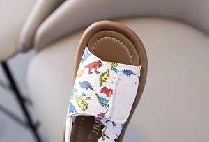 Close-up of kids soft-sole sandals with colorful dinosaur prints and Fashion text.