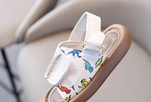 Close-up of toddler sandal featuring colorful dinosaur print and adjustable velcro strap
