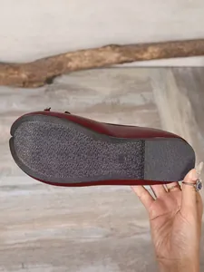 Macro view of the textured non-slip sole and flexible burgundy leather of Tabi flats.