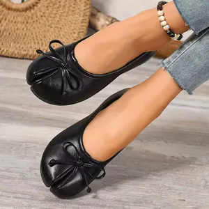 Detailed view of black split-toe Tabi style flat shoes with an elegant bow accent