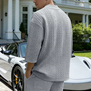 Detail der dicken Zopfstrick-Textur auf dem Rücken eines grauen Oversize-Herrenshirts