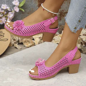 Dettaglio ravvicinato di eleganti sandali rosa con fiori e motivi traforati e tacchi.