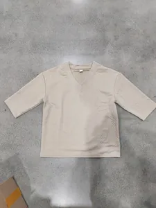 Detailansicht eines beigen V-Ausschnitt-T-Shirts mit strukturiertem Strickmuster.