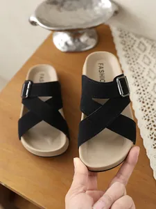 Detailaufnahme schwarzer Kunstleder-Sandalen mit Kreuzriemen und verstellbarer Metallschnalle