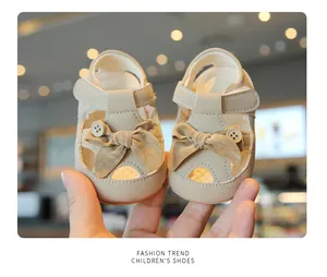 Close-up view of beige baby girl summer walking sandals with bow and button details
