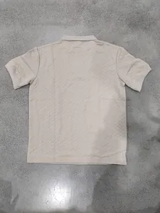 Rear view of textured beige short sleeve polo shirt with chevron jacquard pattern.