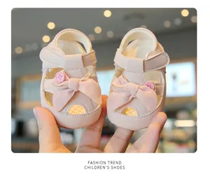 Close-up view of pink baby girl sandals featuring a soft bow and button detail