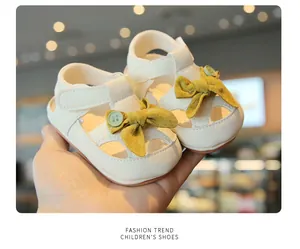Close-up of cream baby sandals with yellow bow and closed-toe design for girls