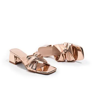 Elegant metallic rose gold block heel sandals featuring a stylish knotted bow strap.