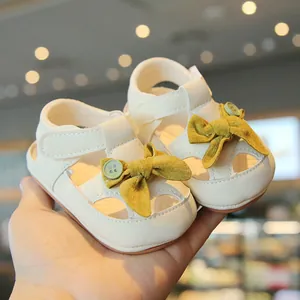 Elegant cream baby walking sandals with yellow bow and protective closed toe design