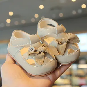 Adorable beige baby walking sandals featuring a soft bow and protective closed-toe