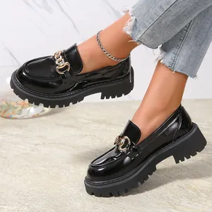 Λεπτομέρεια μαύρων λουστρίνι loafers με πλατφόρμα και χρυσή αλυσίδα σε μοντέλο