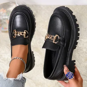 Λεπτομερής προβολή μαύρων loafers πλατφόρμας με χρυσή αλυσίδα και μοντέρνα τρακτερωτή σόλα.