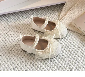 Détail de chaussures de princesse crème avec brides en perles et nœud en dentelle.