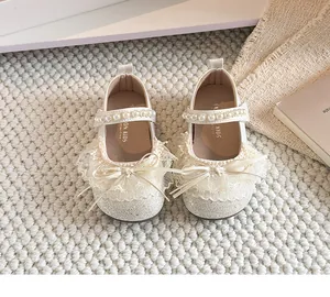 Détail de chaussures de princesse pour fille avec nœuds en dentelle et perles.