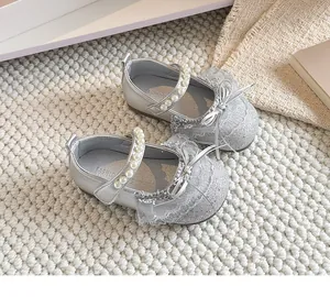 Gros plan de chaussures de princesse argentées pailletées avec perles et nœud en dentelle