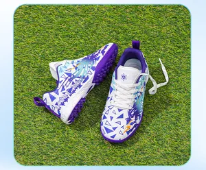 Detailed macro view of children's purple and white turf soccer shoes on artificial grass