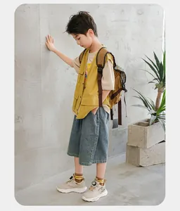 Vue en pied d'un jeune garçon portant des baskets beiges pour enfants dans un cadre lifestyle