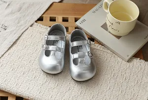 Detalle de zapatos Mary Jane plateados para niña con hebillas dobles y calados