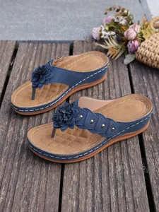 Detailopname van blauwe sandalen met sleehak, bloem en stijlvolle metalen klinknagels