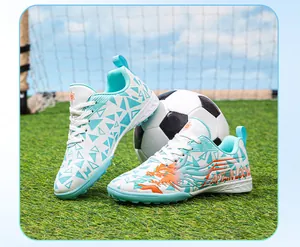 Detailed view of white and cyan children's TF soccer cleats on green grass