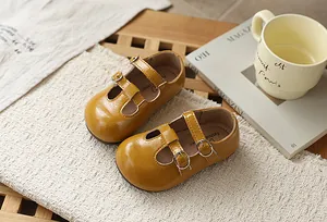 Primer plano de zapatos Mary Jane franceses amarillos para niñas con correas de hebilla